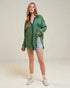 Woman wearing a green shirt and denim shorts on a plain background
