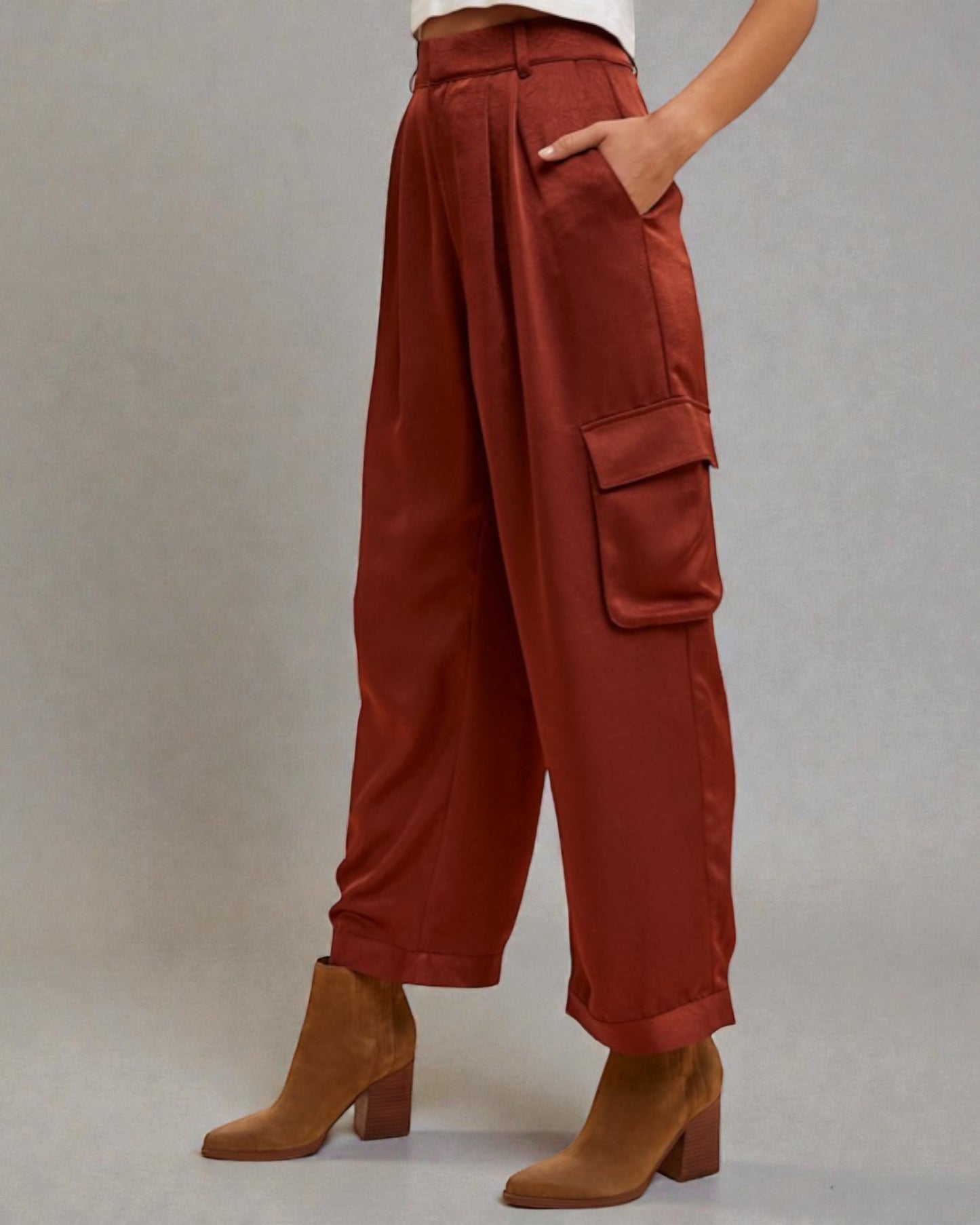 Person wearing rust-colored wide-leg pants with pockets on a plain background