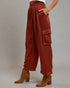 Person wearing rust-colored wide-leg pants with pockets on a plain background