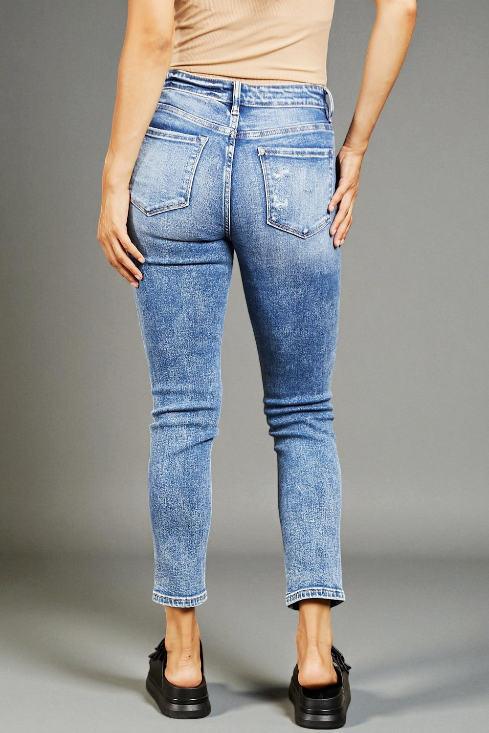 Person wearing blue jeans on a gray background