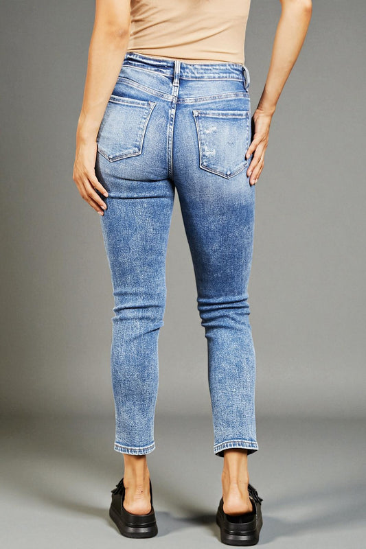 Person wearing blue jeans on a gray background