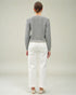 Person wearing a gray sweater and white pants on a plain background