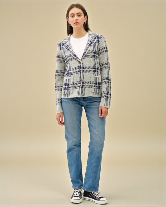 Person wearing a plaid jacket and blue jeans on a beige background