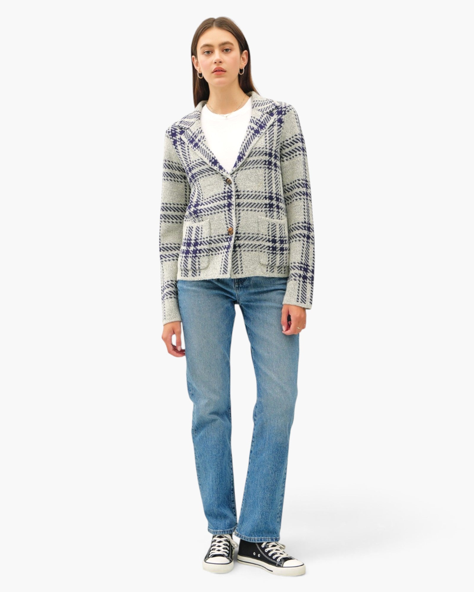 A woman modeling a gray and navy plaid tweed blazer over a white t-shirt, paired with blue jeans and black sneakers, against a plain white background.