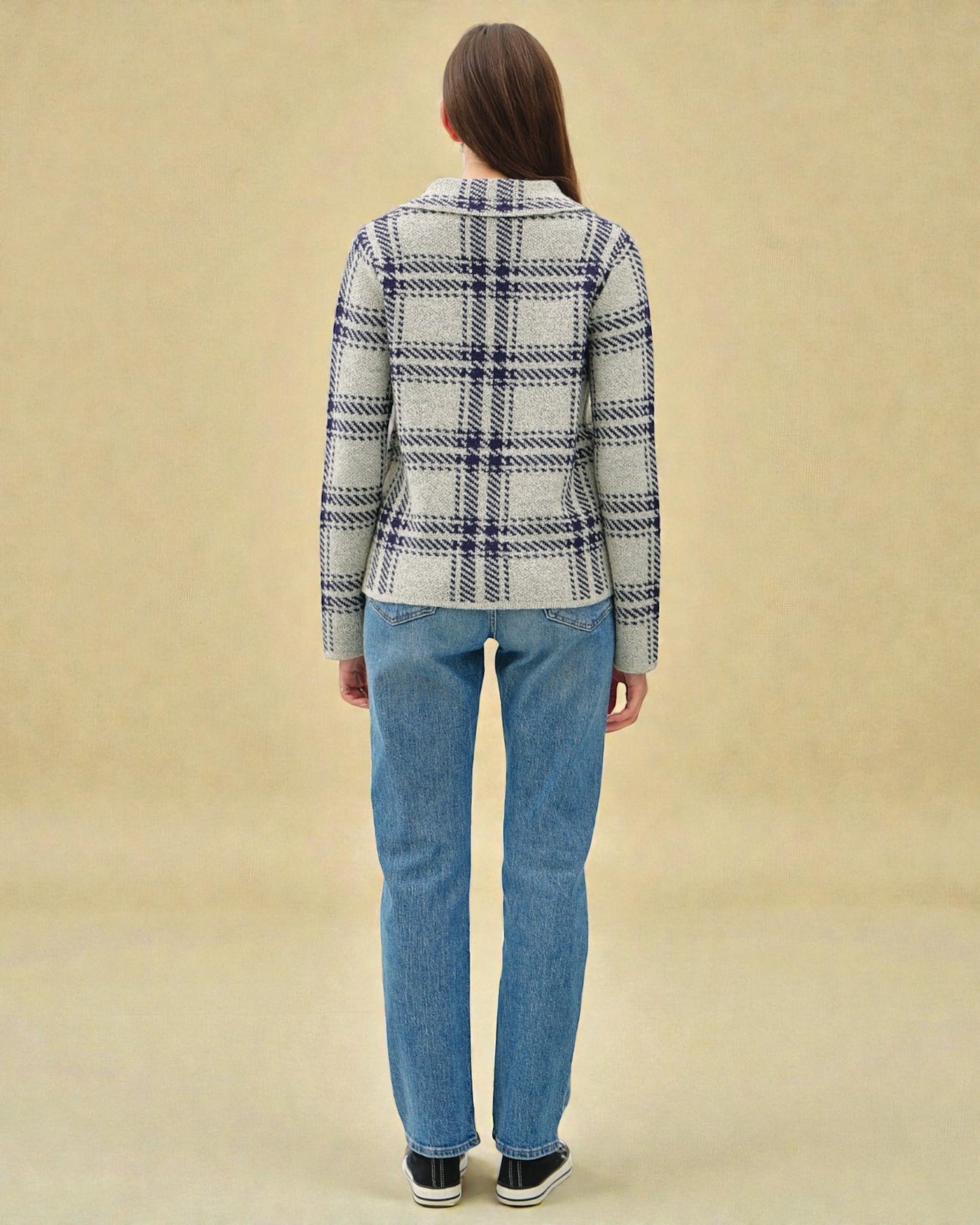 Person wearing a plaid shirt and jeans on a beige background