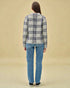 Person wearing a plaid shirt and jeans on a beige background