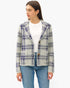 A woman modeling a textured tweed blazer with a navy and gray plaid pattern, worn over a white mock neck top and blue jeans, against a plain white background.