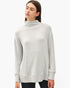 A woman wearing a light gray heathered mock neck sweater, shown from the waist up against a plain white studio background.