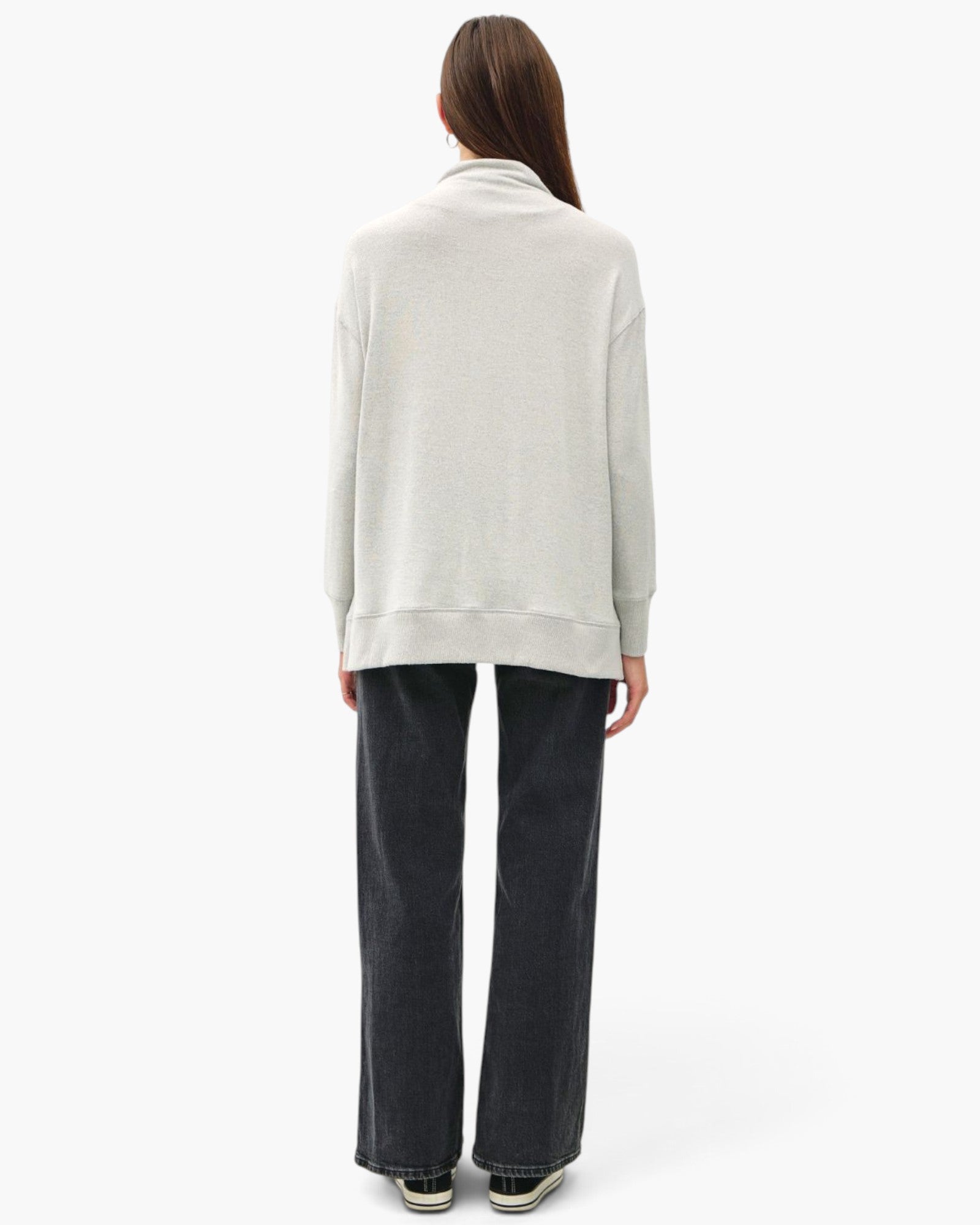 A model shown from the back wearing a light gray heathered cowl-neck sweatshirt and dark charcoal wide-leg jeans against a plain white studio background.
