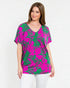 Woman wearing a pink and green patterned top on a white background