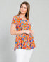 Woman wearing a colorful floral blouse against a gray background