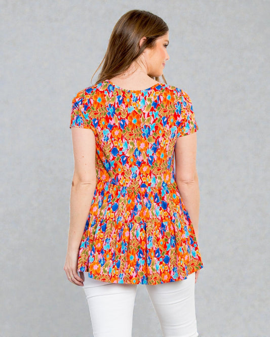 Woman wearing a colorful floral blouse against a gray background