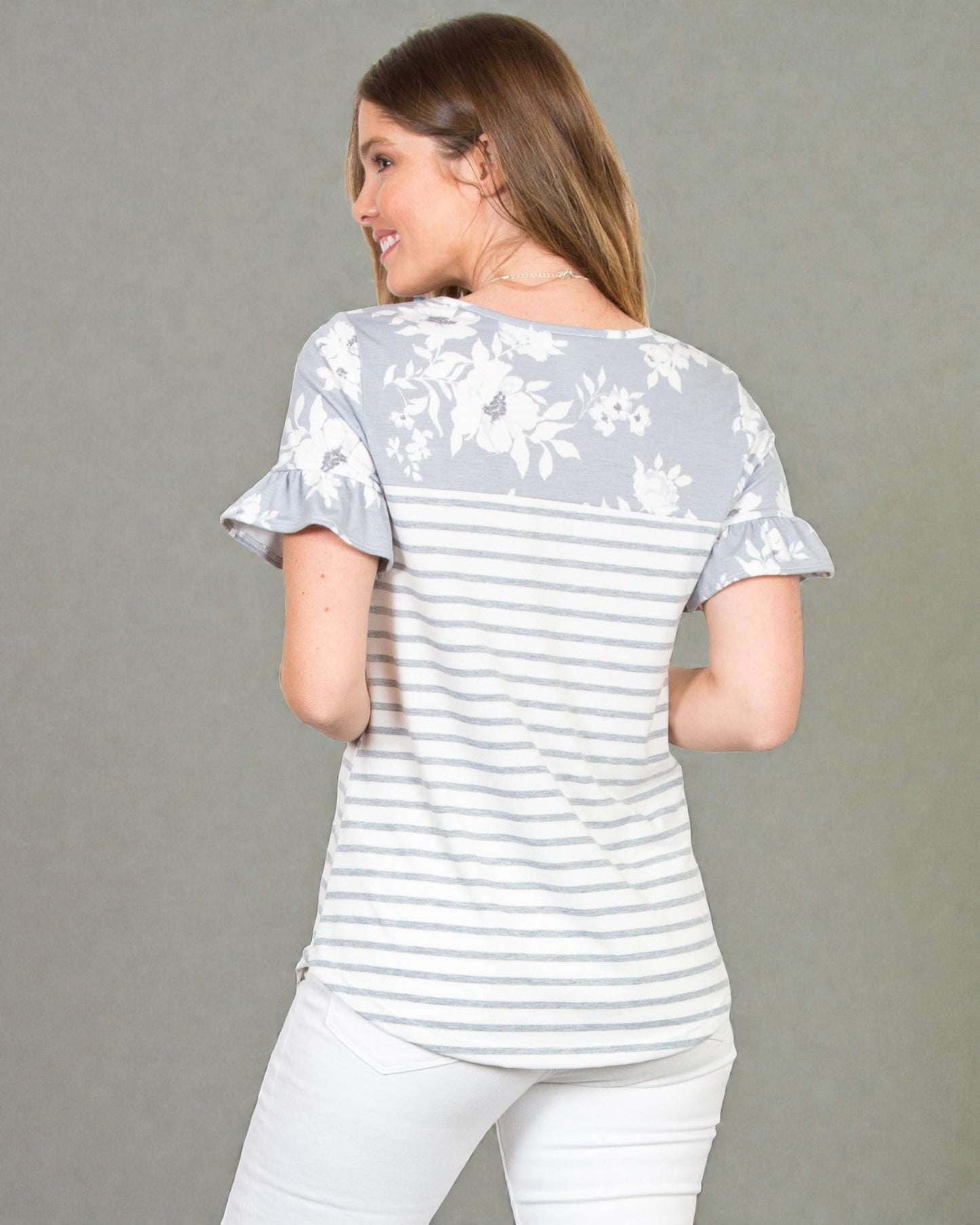 Woman wearing a light gray and white striped shirt with floral sleeves on a gray background