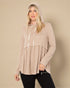 Woman wearing a beige hooded top against a beige background
