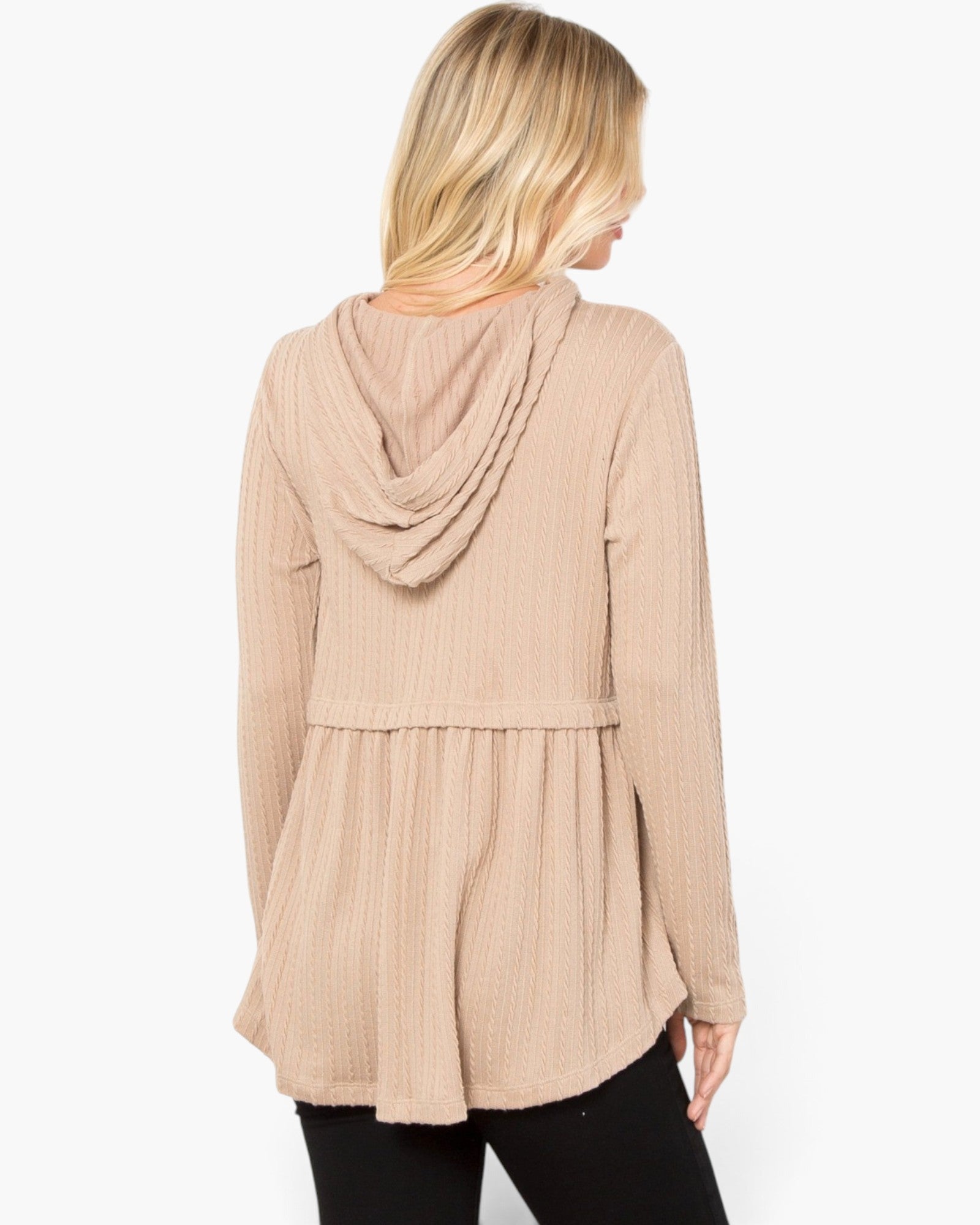 A woman shown from the back wearing a beige ribbed knit hooded long-sleeve top with a peplum waist, paired with black pants, against a plain white background.