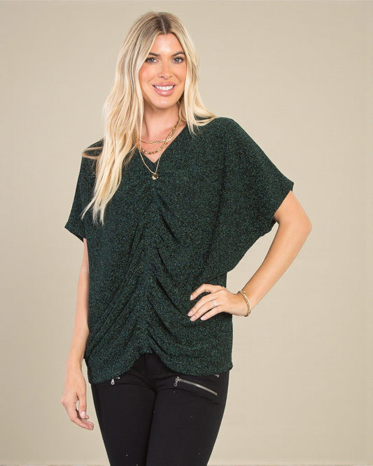 Woman wearing a green knitted top against a beige background