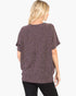 A woman shown from the back wearing a loose, short-sleeve knit top with a mottled purple and black pattern, paired with black pants, against a plain white background.
