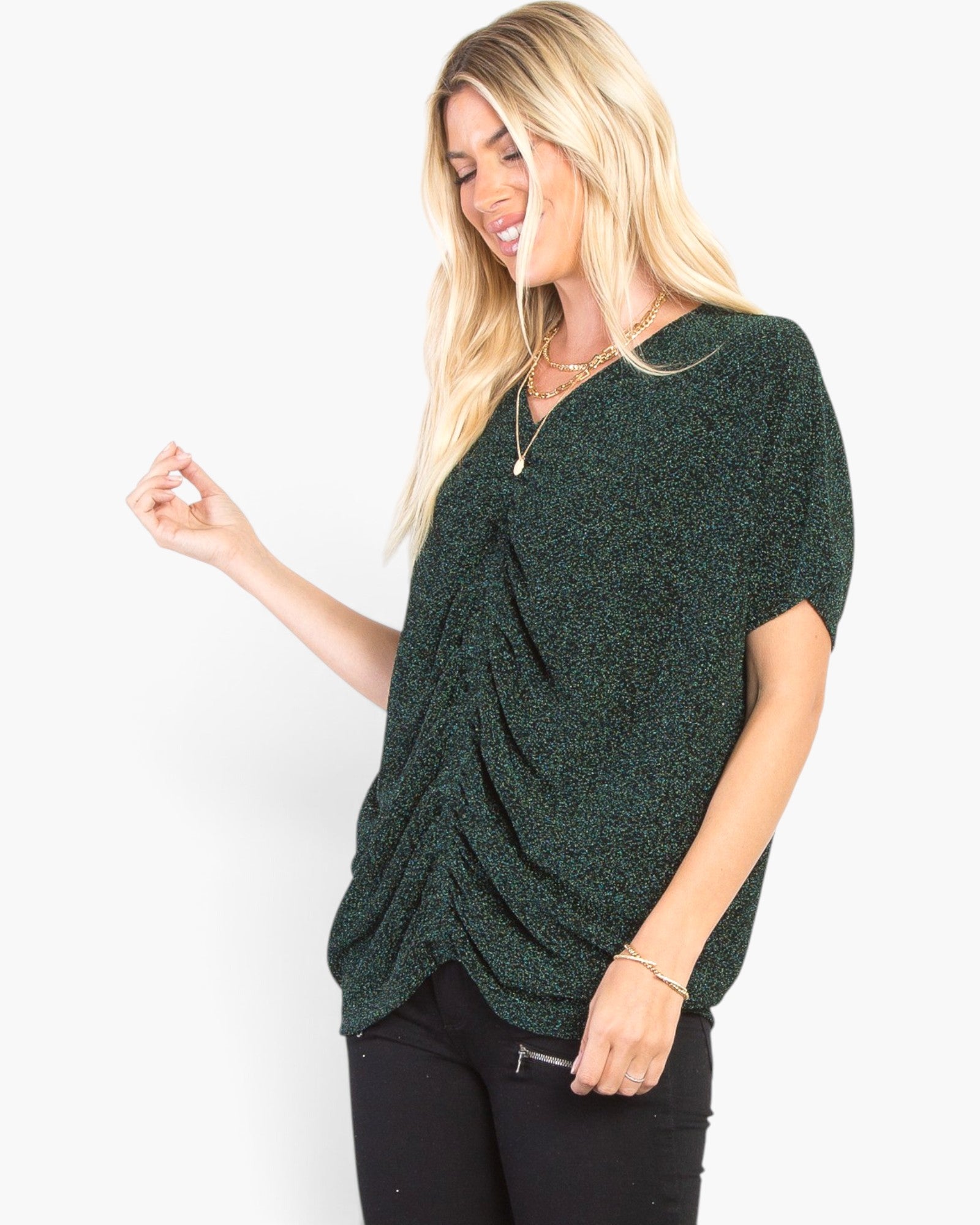 A woman modeling a dark green short-sleeve knit top with a textured, heathered pattern and a draped twist detail at the front, paired with black pants against a plain white background.