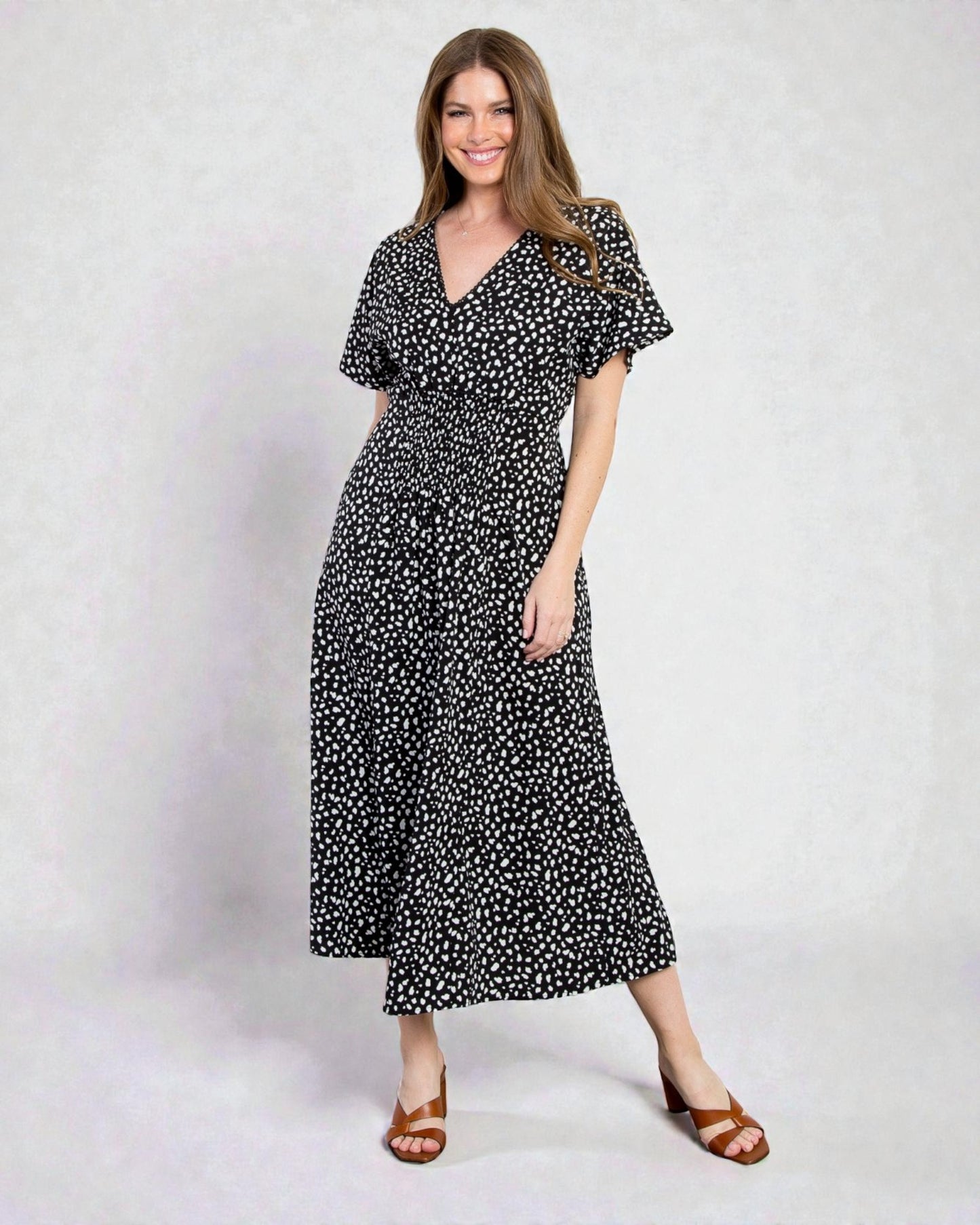 Woman wearing a black and white patterned dress on a plain background