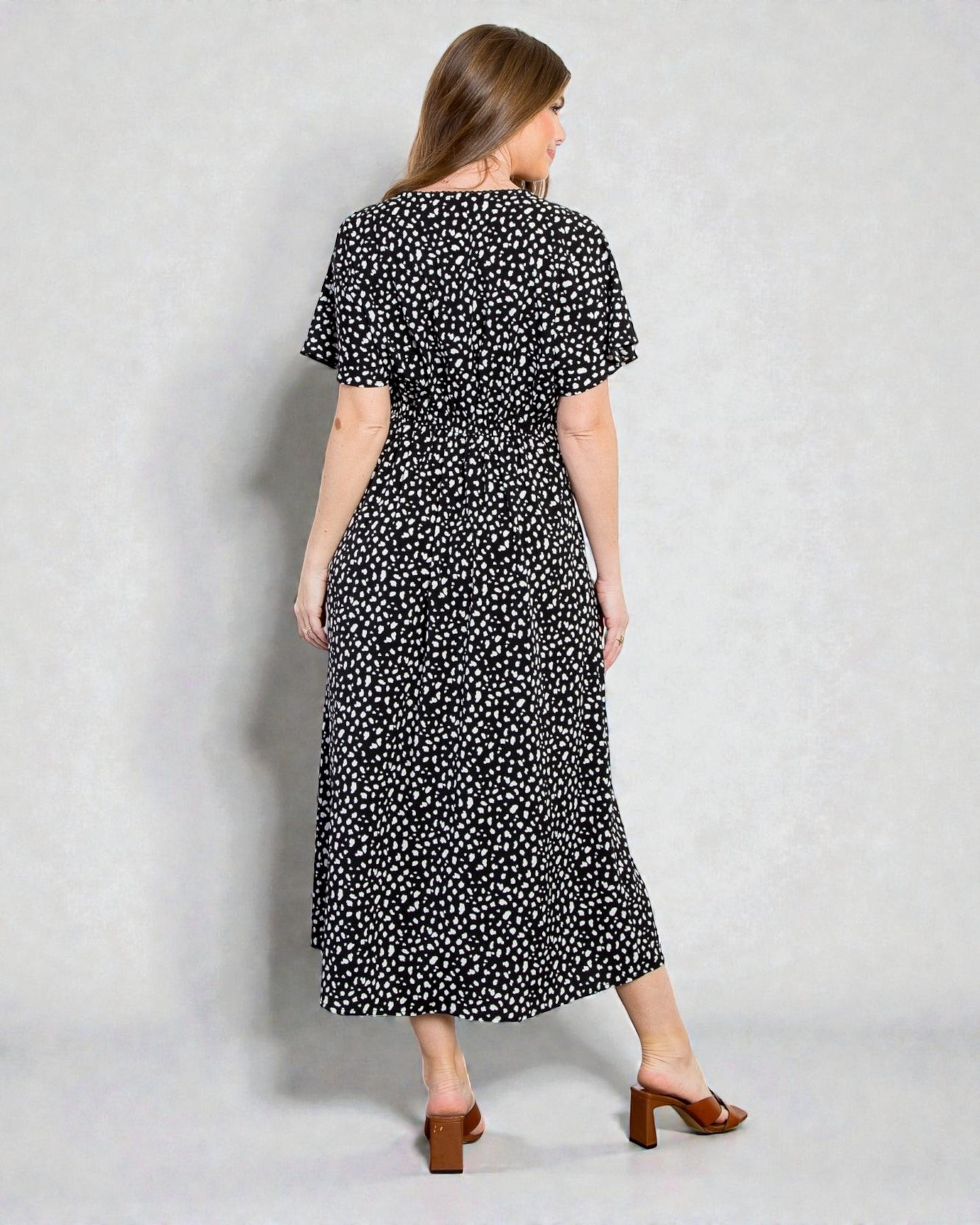 Woman wearing a black dress with white polka dots against a plain background