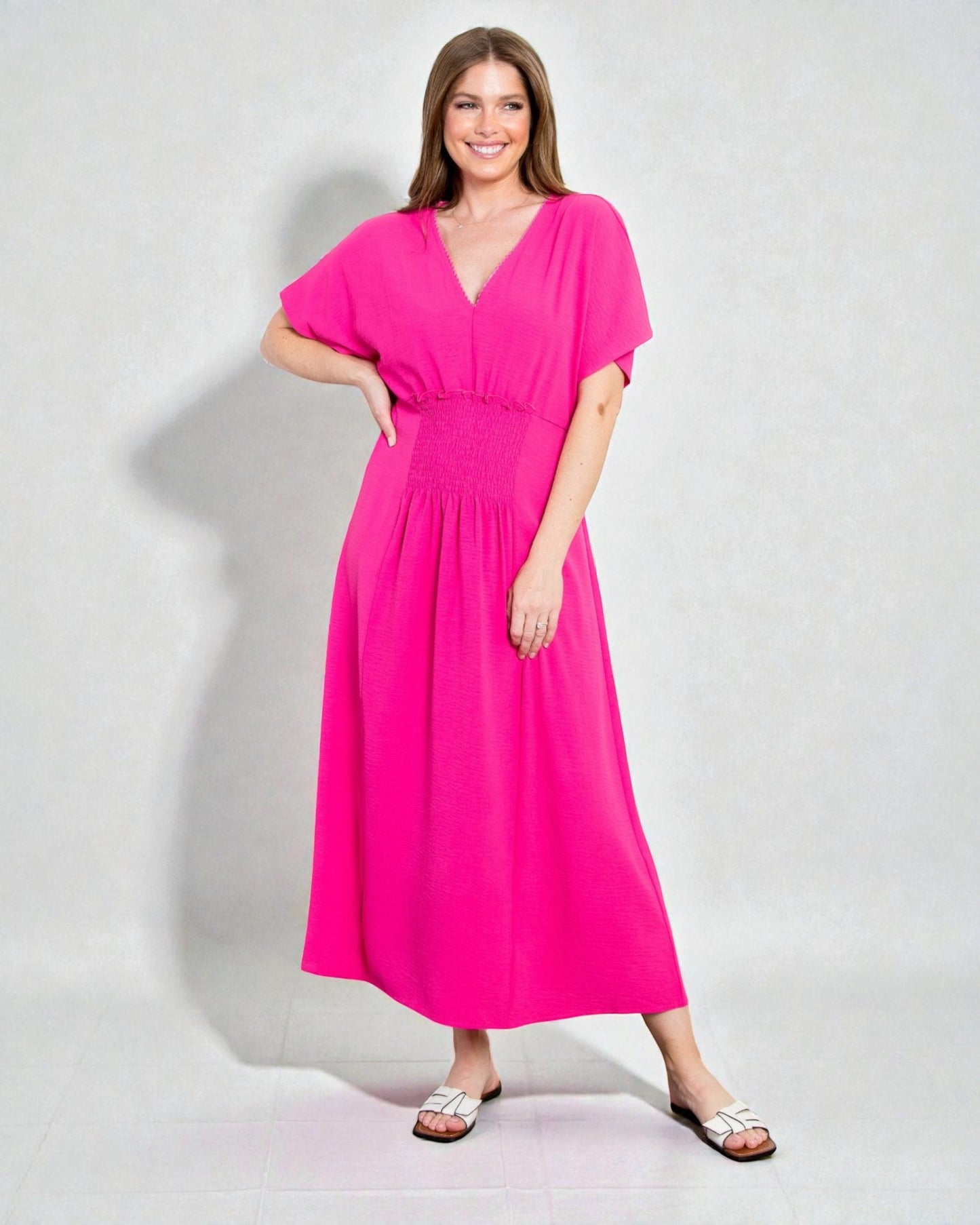 Woman wearing a bright pink dress against a plain background