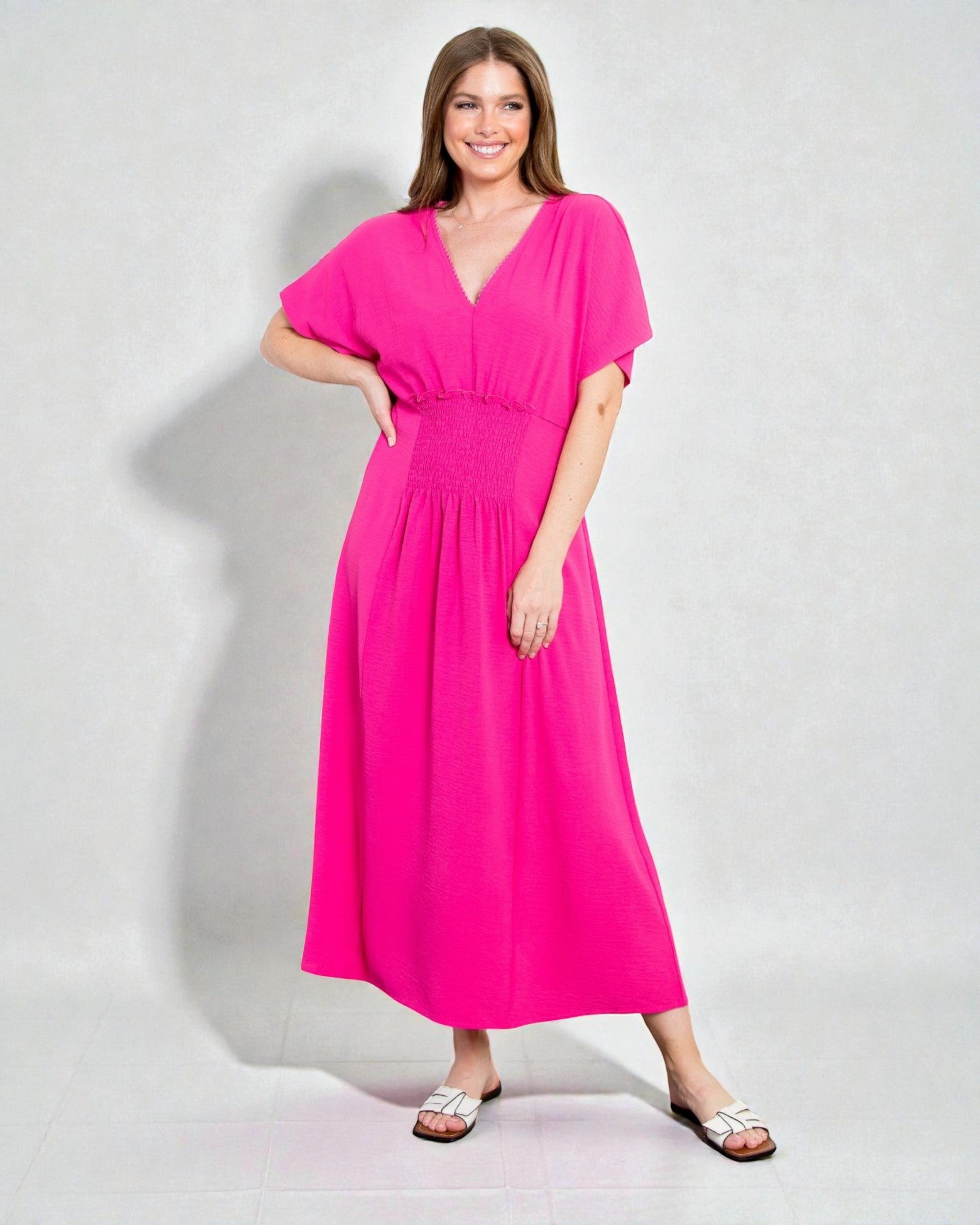 Woman wearing a bright pink dress against a plain background