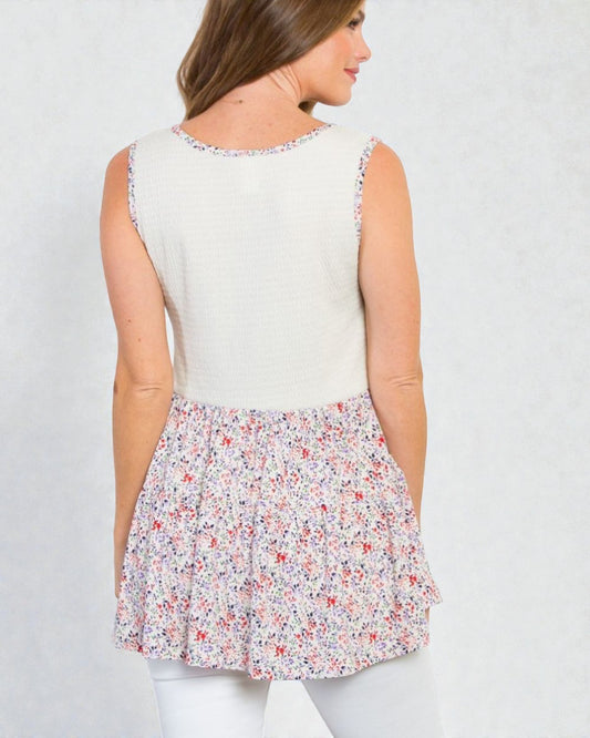 Woman wearing a sleeveless top with a floral skirt on a plain background