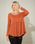 Woman wearing a rust-colored long-sleeve top against a neutral background