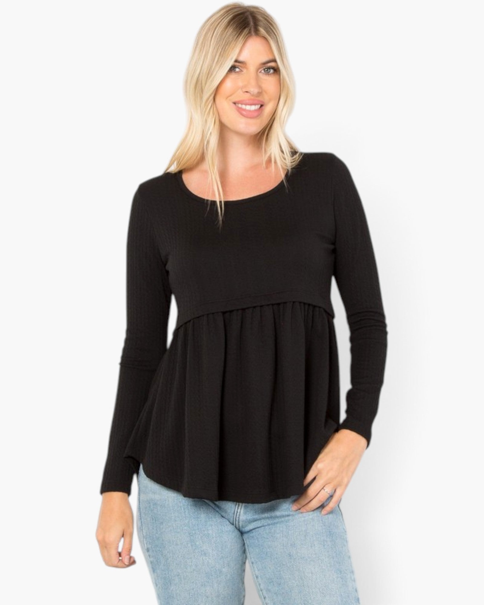 A woman modeling a black long-sleeve peplum top with a scoop neckline, paired with light blue jeans, against a plain white background.