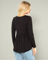 Woman wearing a black long-sleeve top with a subtle pattern on a plain background