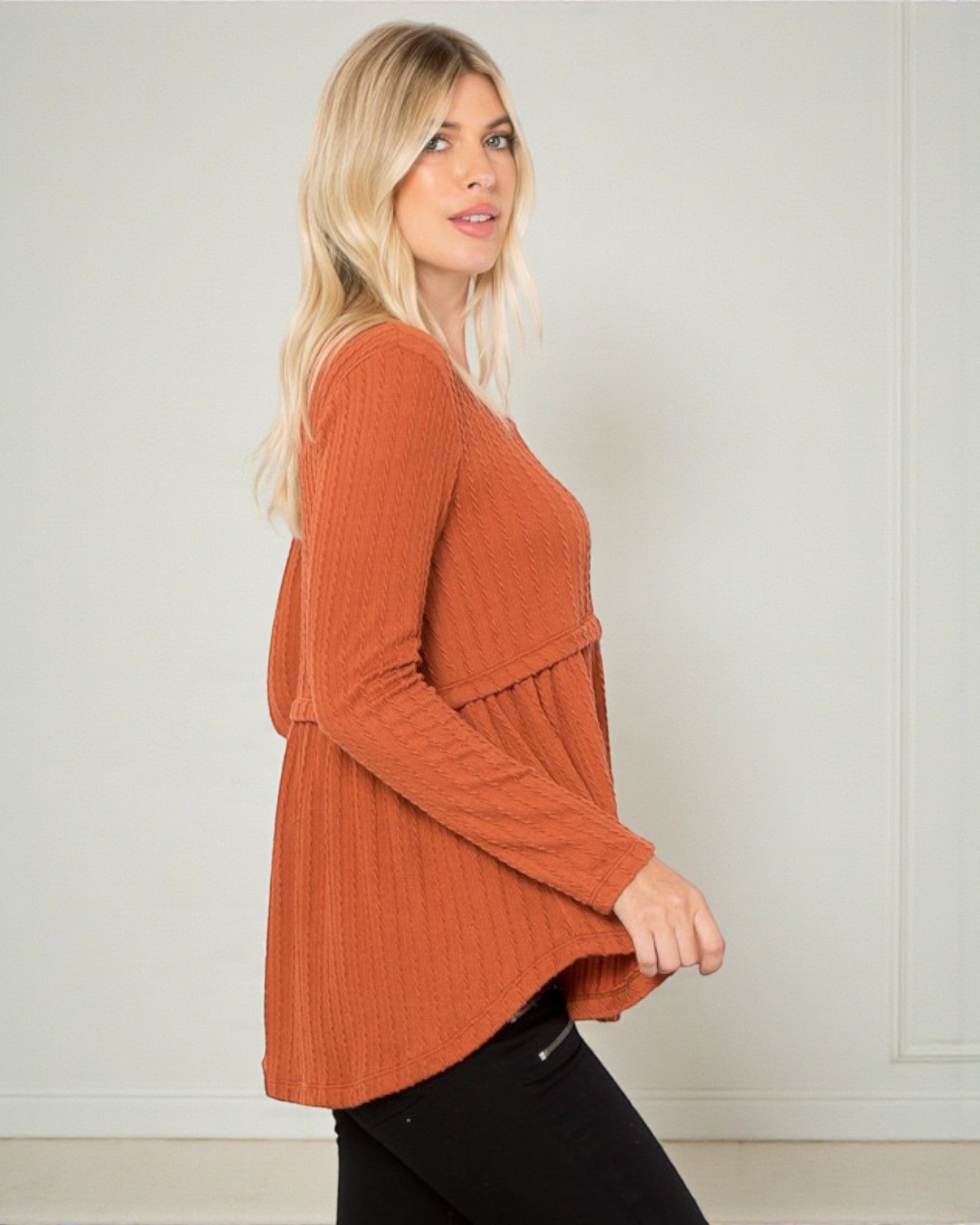 Woman wearing a rust-colored ribbed sweater against a plain background