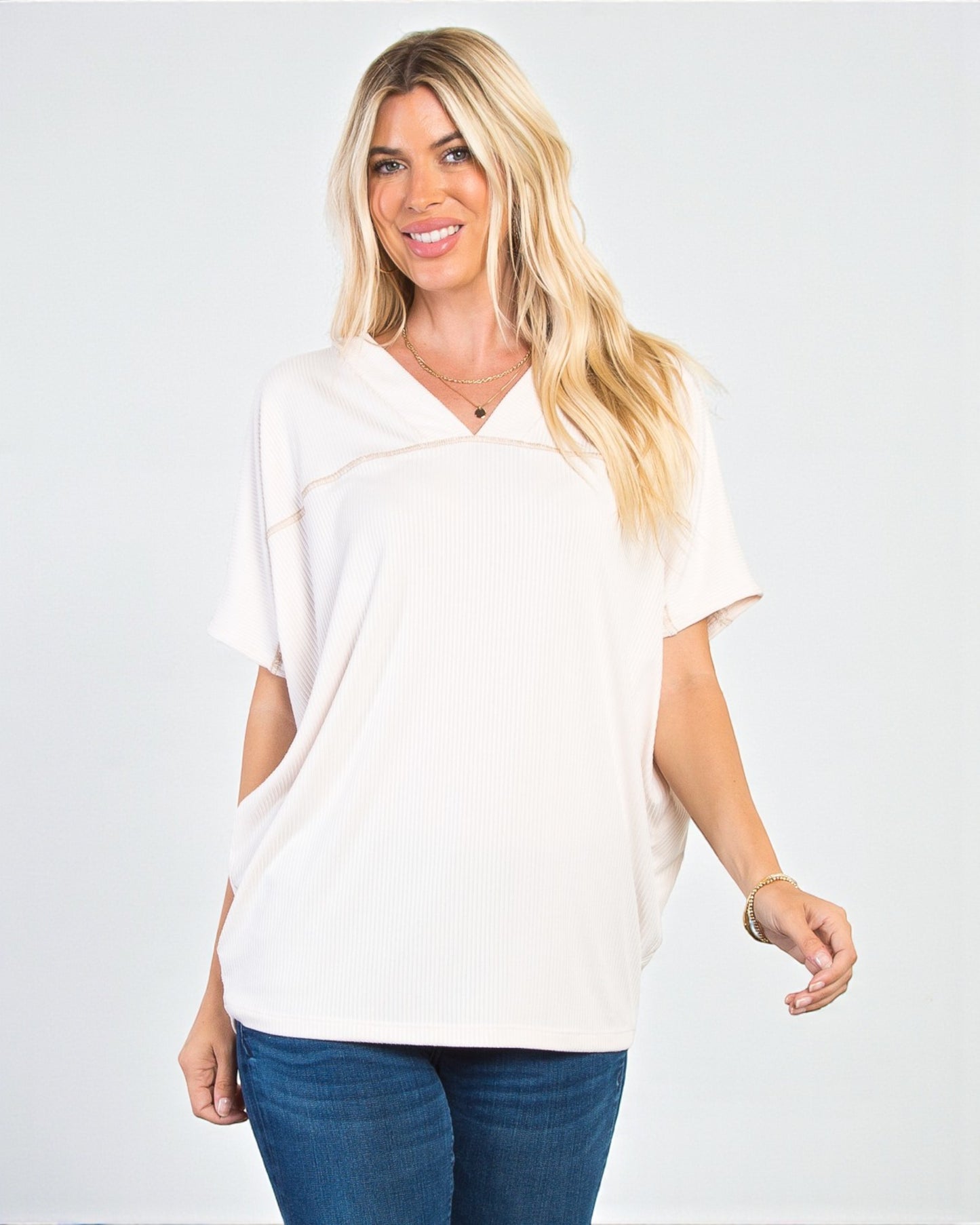 Woman wearing a white blouse and blue jeans on a plain background