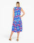 A woman modeling a sleeveless midi dress with a vibrant tropical leaf print in blue, pink, and white, shown from the back against a plain white background.