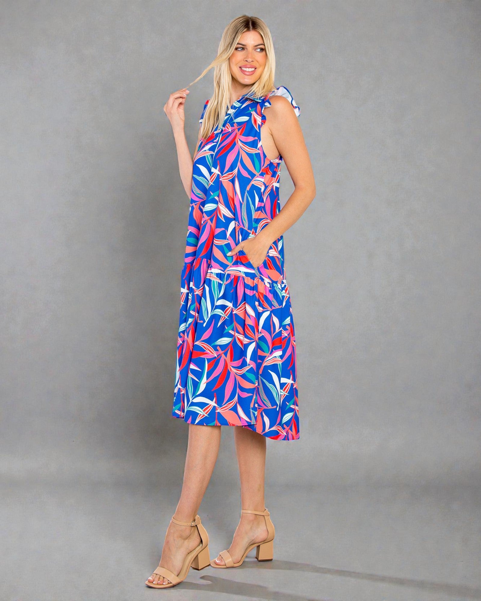 Woman wearing a colorful dress with a floral pattern on a gray background