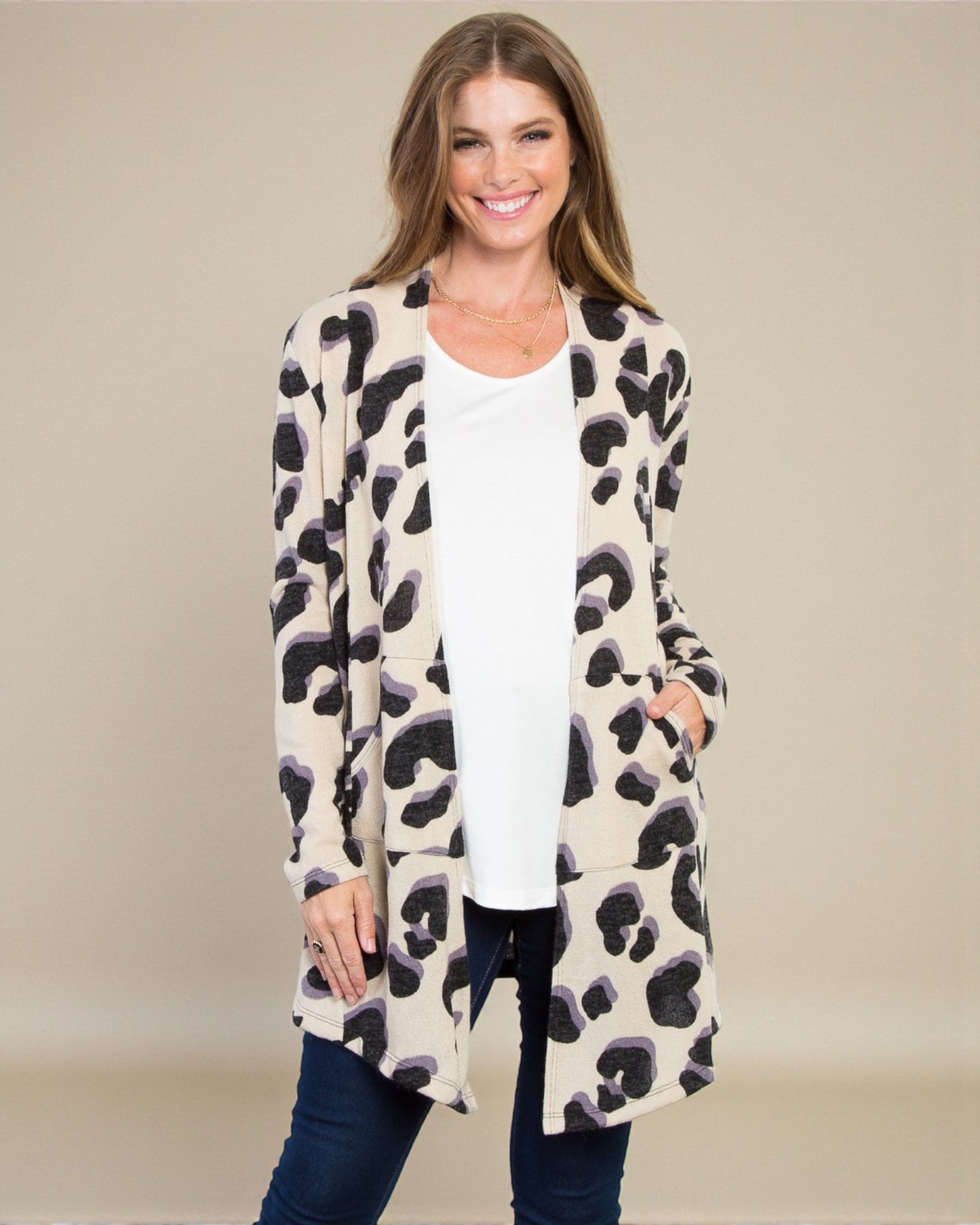 Woman wearing a leopard print cardigan over a white top and jeans on a beige background
