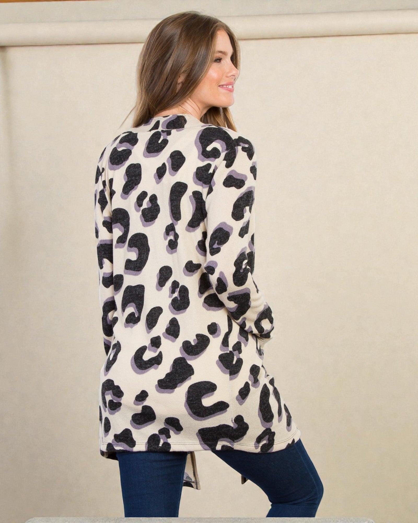 Woman wearing a leopard print cardigan against a beige background