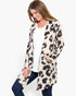 A woman modeling a long-sleeve open-front cardigan with an abstract leopard-like print in beige, black, and gray, worn over a white top and dark blue jeans against a plain white background.