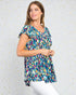 Woman wearing a colorful patterned top against a light gray background