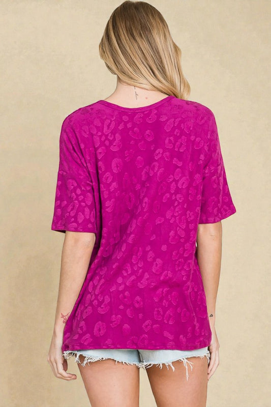 Person wearing a purple leopard print top with a beige background