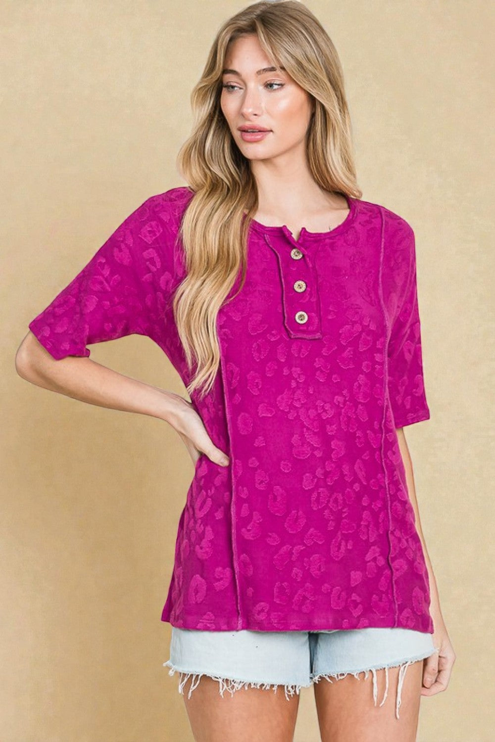 Woman wearing a pink patterned top with a beige background