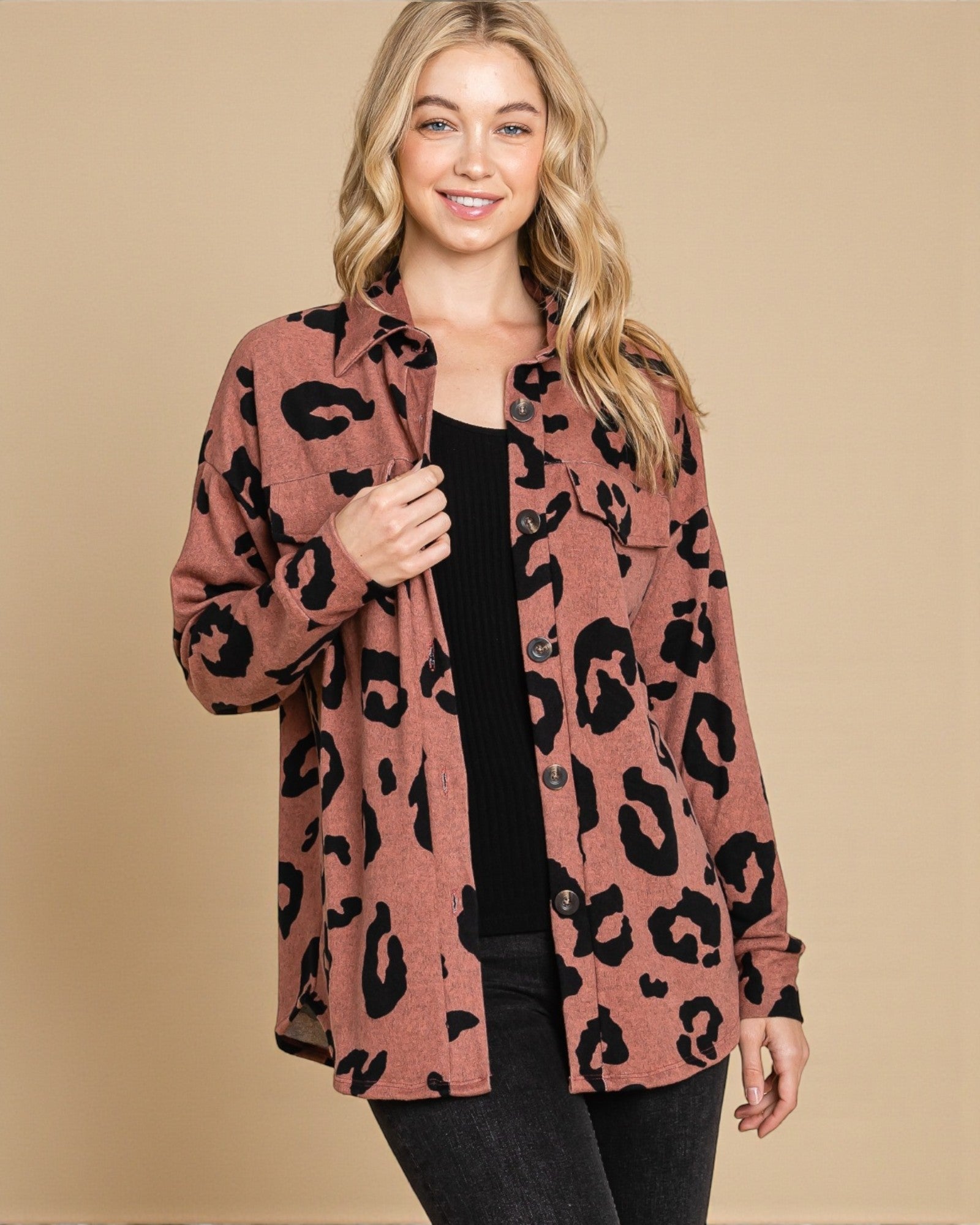Woman wearing a leopard print cardigan against a beige background