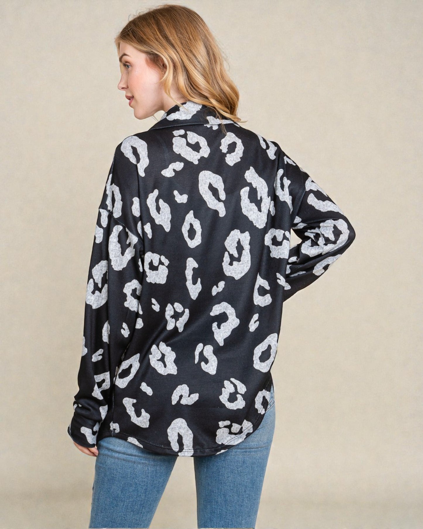 Woman wearing a black shirt with white leopard print pattern on a beige background