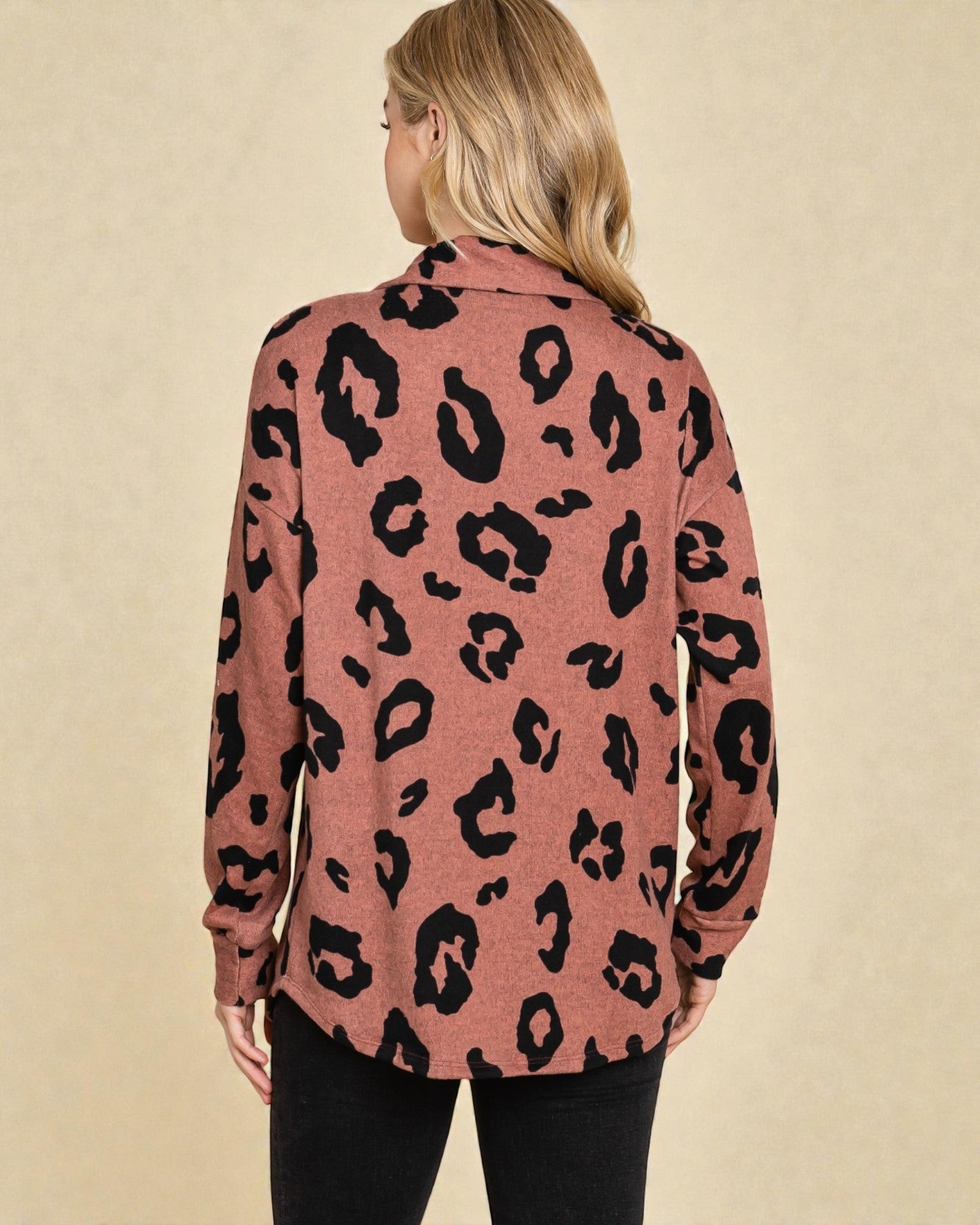 Person wearing a pink sweater with black leopard print on a beige background