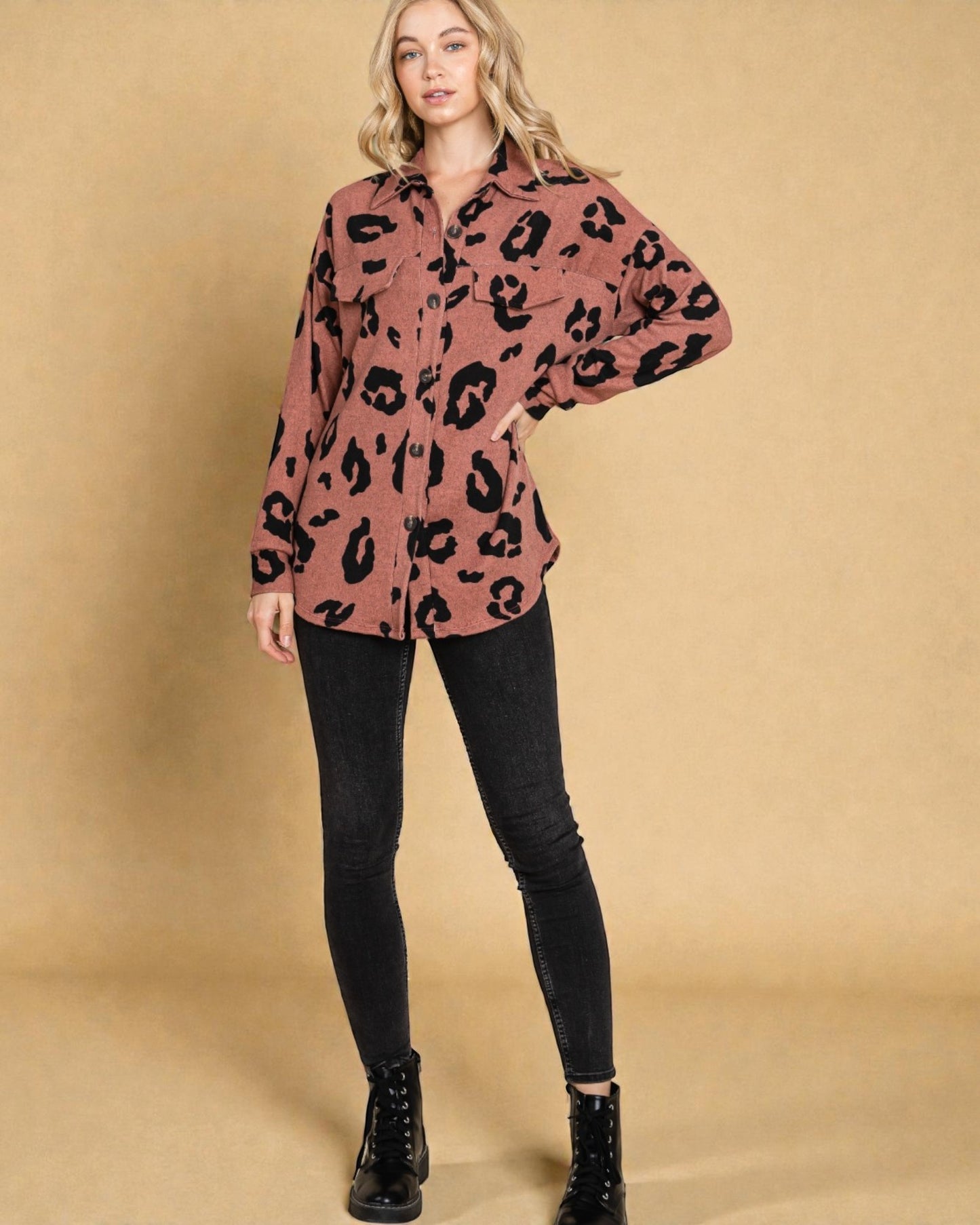Person wearing a pink leopard print shirt with black pants on a beige background