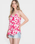 Woman wearing a pink and white patterned tank top and denim shorts on a white background