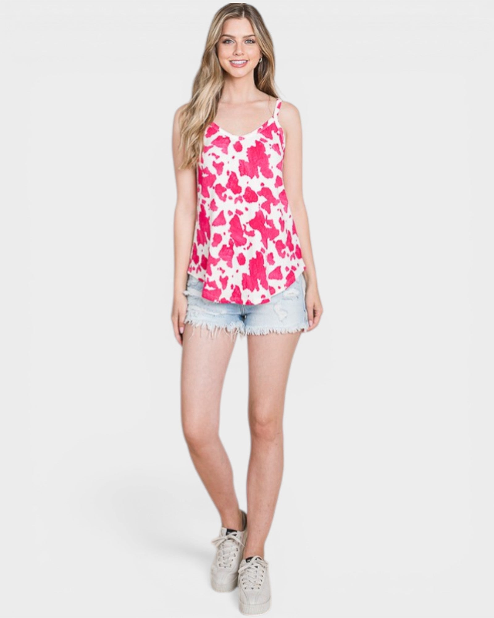 Woman wearing a pink floral tank top and denim shorts on a white background