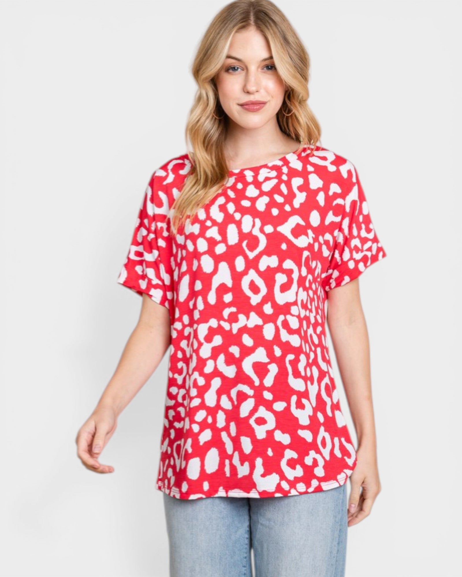 Woman wearing a red and white leopard print top on a plain background
