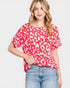 Woman wearing a red leopard print top and blue jeans on a light gray background