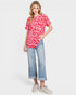 Woman wearing a red leopard print top and blue jeans on a white background