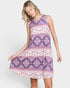 Woman wearing a sleeveless purple patterned dress on a white background